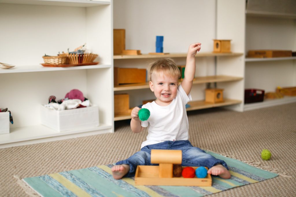 child toddler plays with balls and cylinders