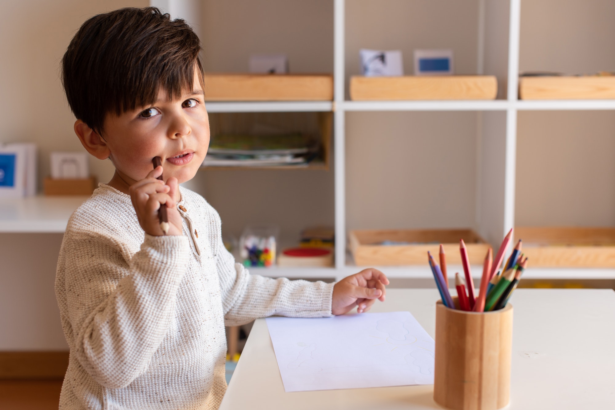 Preschooler kid drawing with coloured pencils. Homeschooling. Learning community. Montessori school.