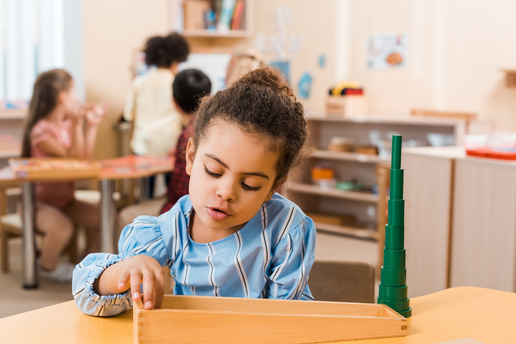 Selective focus of african american kid playing wooden game at table in montessori school